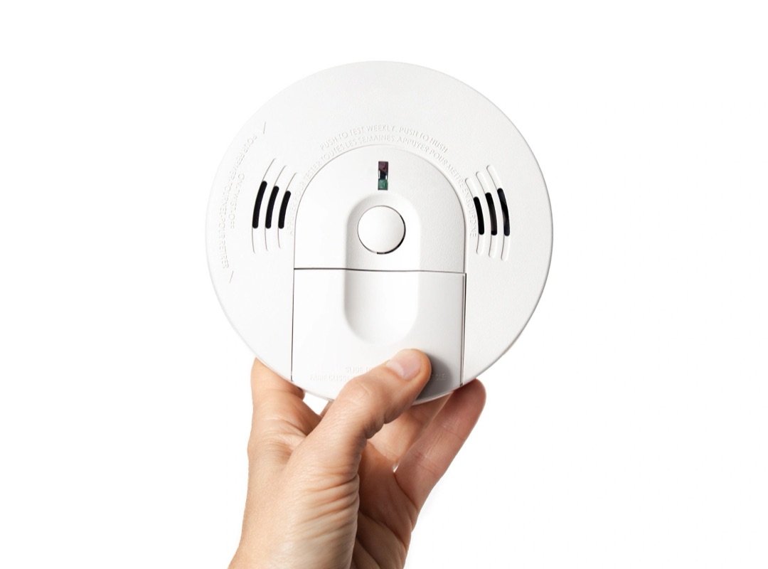 Smoke and carbon monoxide detector held in a hand