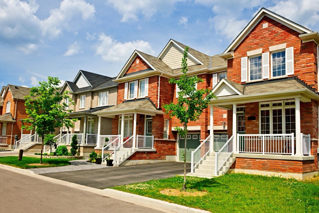 Row of two-story brick townhomes with white trim and porches
